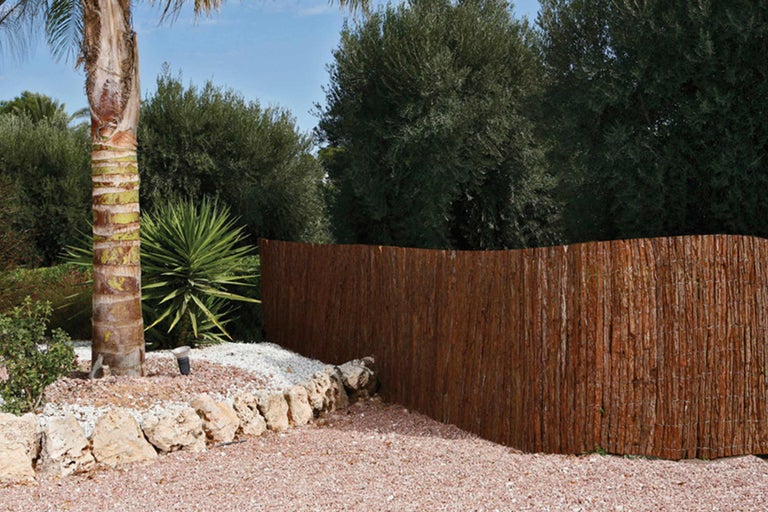 Scène de jardin avec un écran de confidentialité en matériaux naturels, pierres et plantes