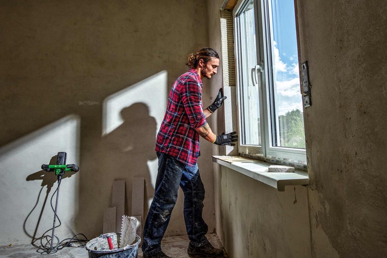 Handwerker beim Einbau eines Fensters in einem Rohbauzimmer