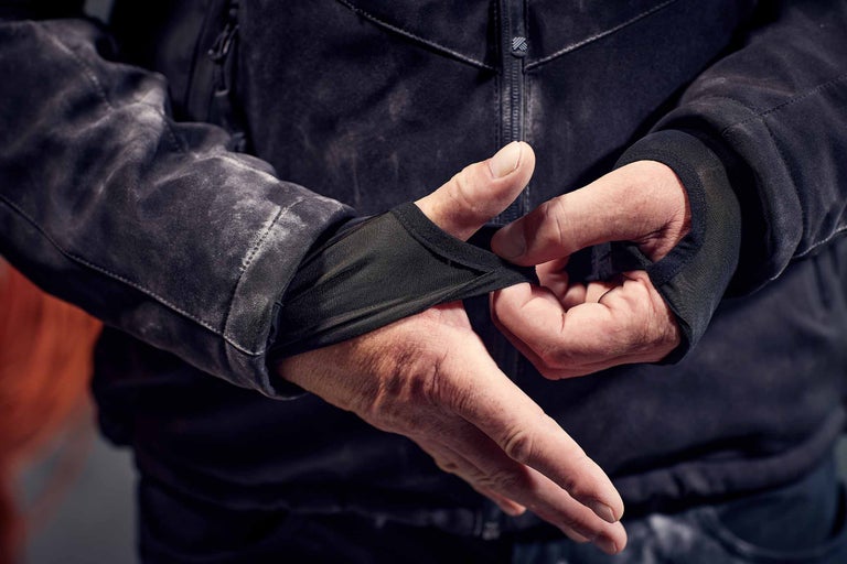Gros plan d'une personne essayant une veste avec des manchettes intégrées.
