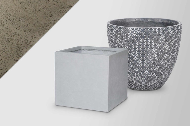 Deux pots de fleurs en ciment : un pot carré et un pot rond avec motif