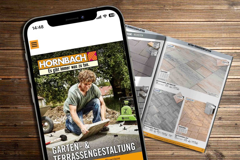 Smartphone avec le site web Hornbach ouvert et un catalogue de dalles de terrasse sur un plancher en bois.