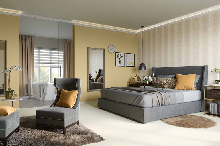 Helles Schlafzimmer mit Bett, Sessel und Badezimmerbereich