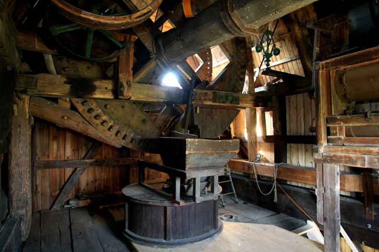 Intérieur d'un moulin historique avec des machines et des transmissions en bois