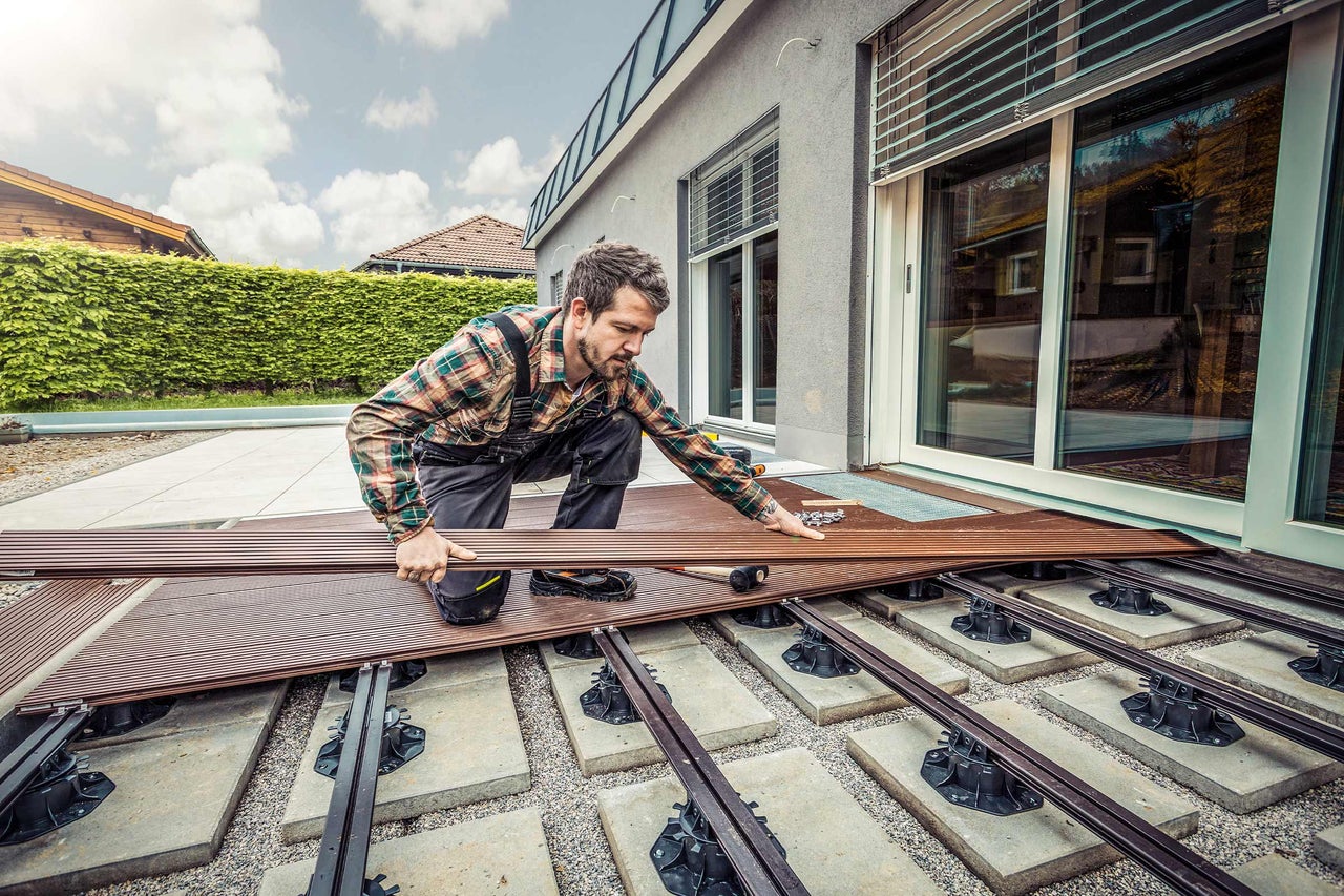 Artisan posant des lames de terrasse sur une sous-construction à l'extérieur