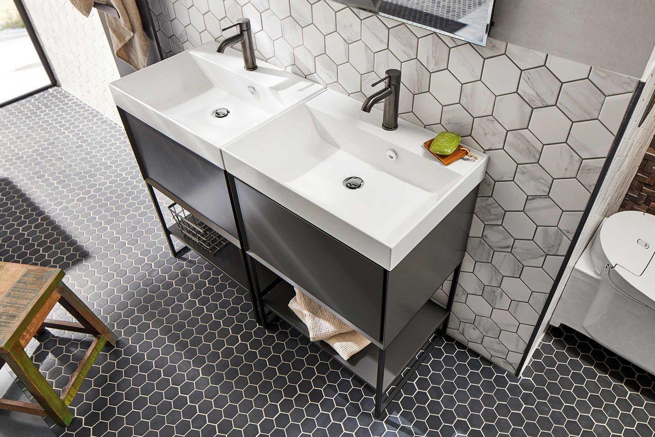Salle de bain avec deux lavabos, meubles bas foncés et carrelage hexagonal