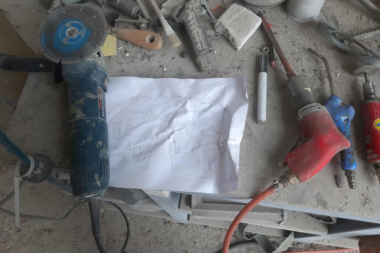 Eine Schleifmaschine, eine Skizze und andere Werkzeuge auf einer Werkbank.