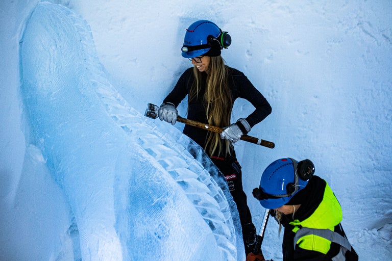 Eiskletterer mit Helm, Handschuhen und Eispickel bei der Arbeit an einer Eiswand