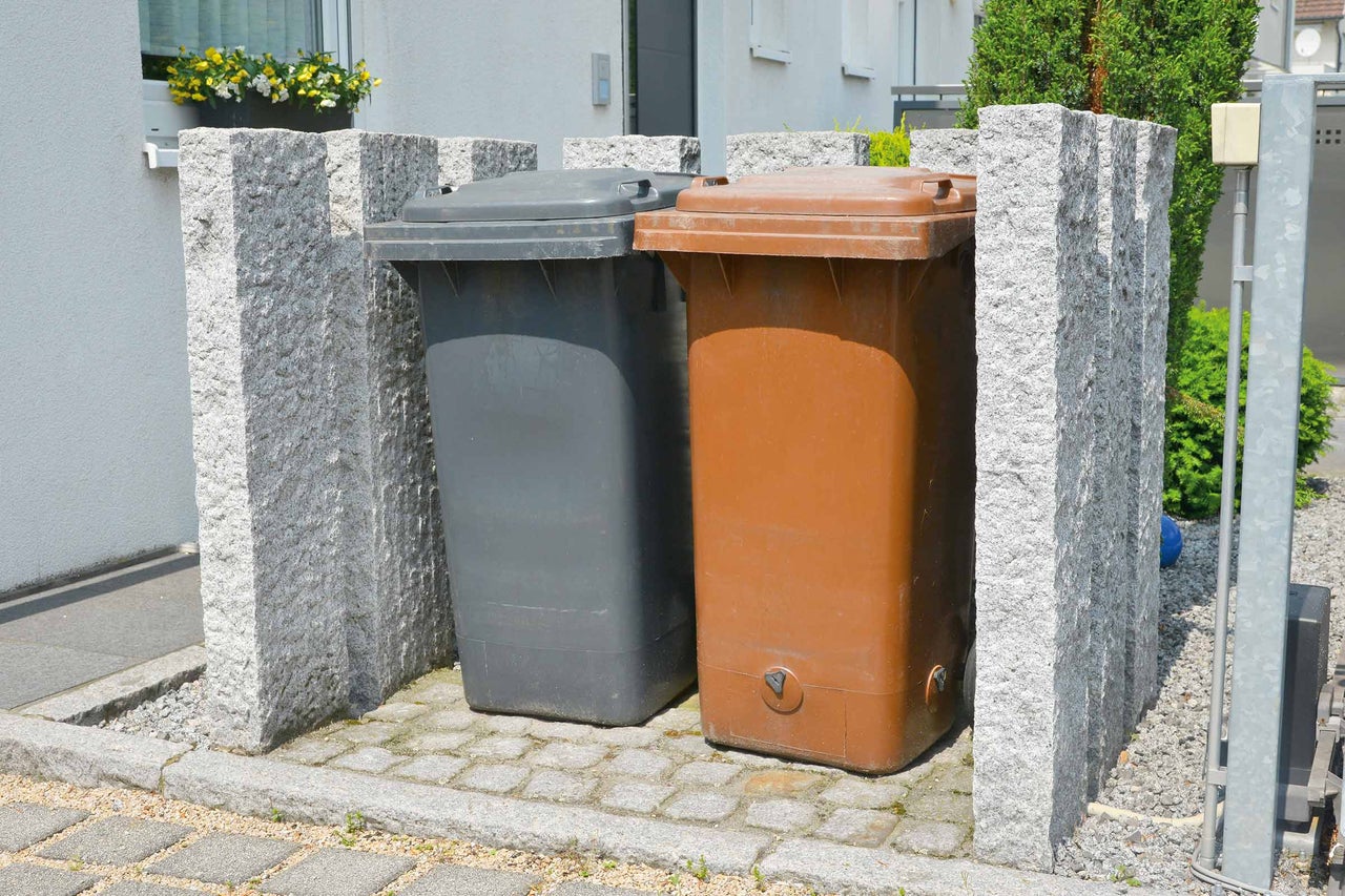 Deux poubelles dans un abri à poubelles en pierre