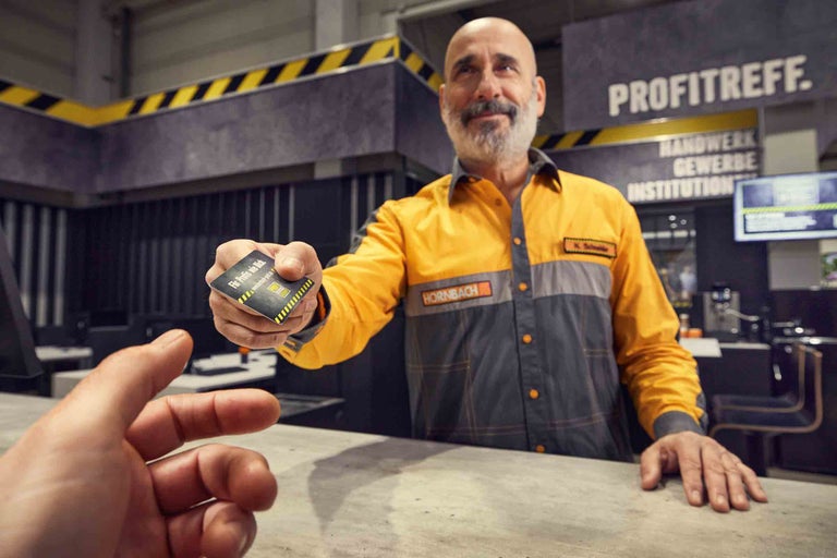 Un employé de Hornbach tend une carte client par-dessus un comptoir.