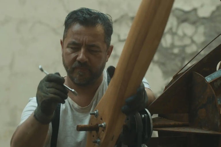 Un homme fixe une hélice en bois avec une clé à molette.