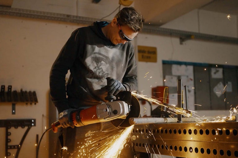 Mann schleift Metall mit einem Winkelschleifer, Funken fliegen