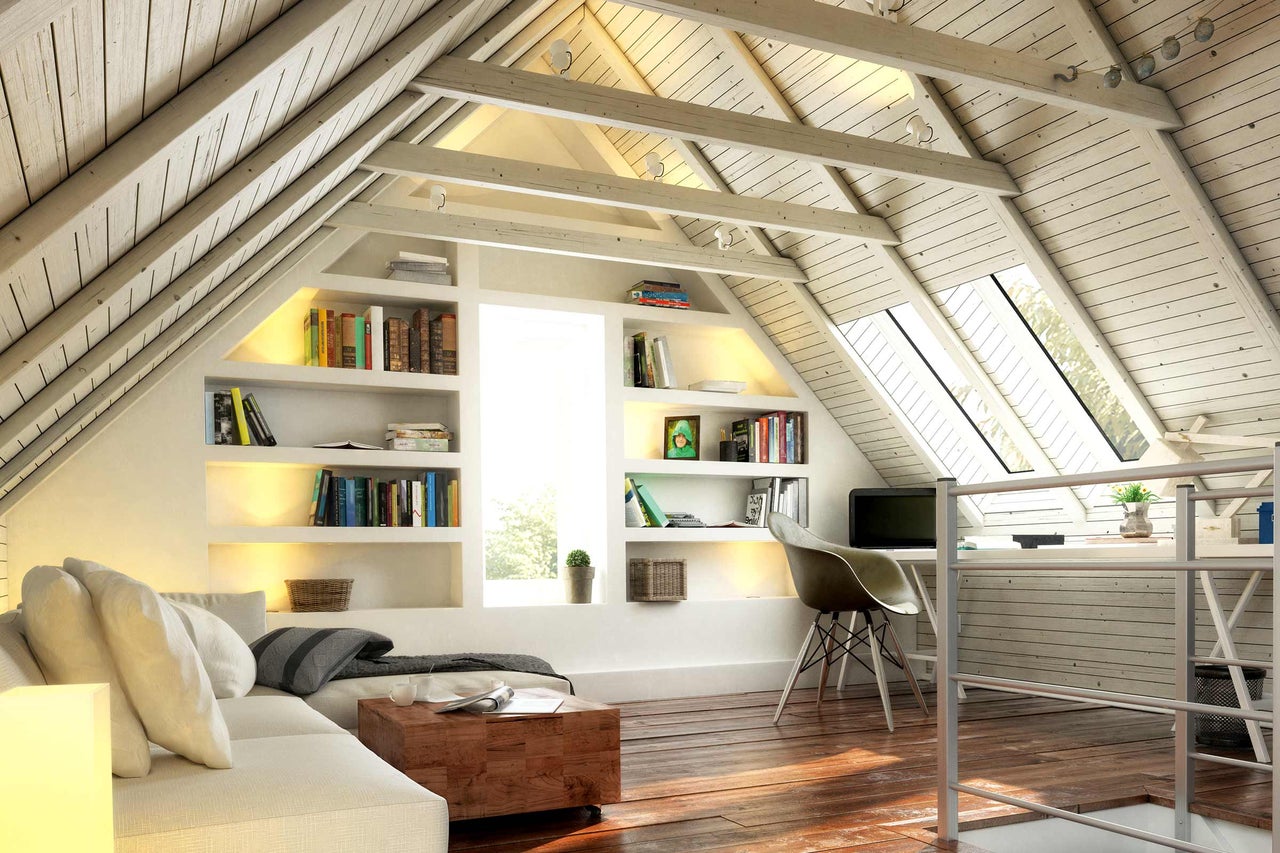 Chambre mansardée lumineuse avec canapé, étagères et bureau