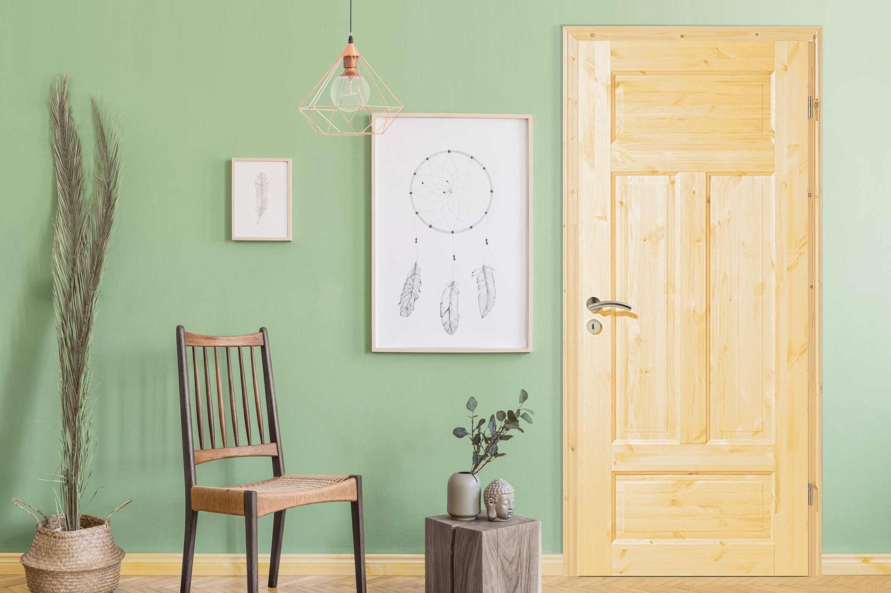 Scène avec porte en bois, chaise, décoration et décorations murales dans une pièce lumineuse.