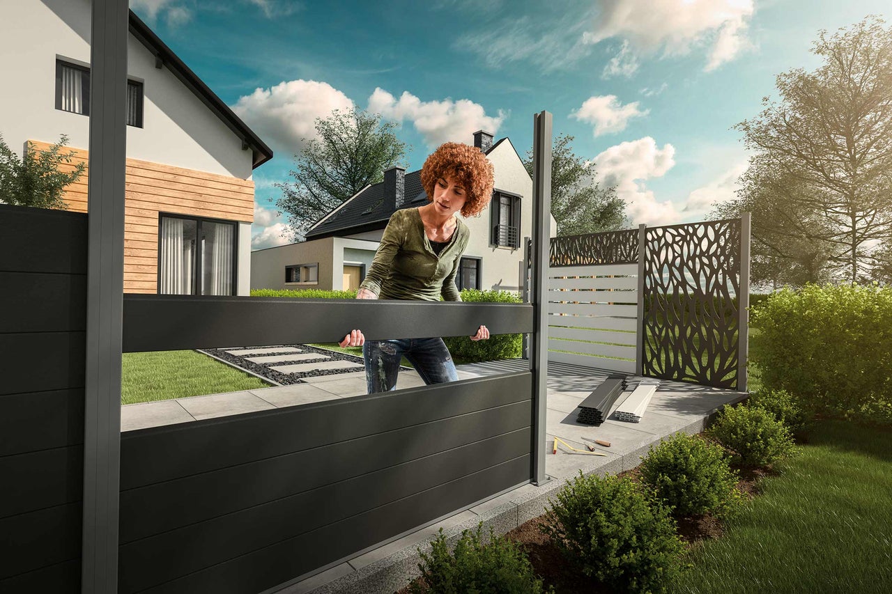 Femme installant un écran de confidentialité dans le jardin.