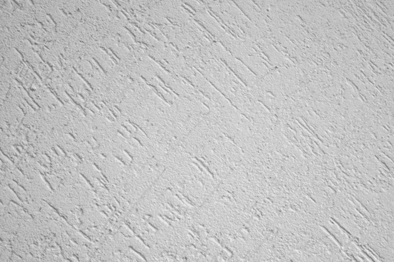 Gros plan d'un mur avec une texture d'enduit gratté.