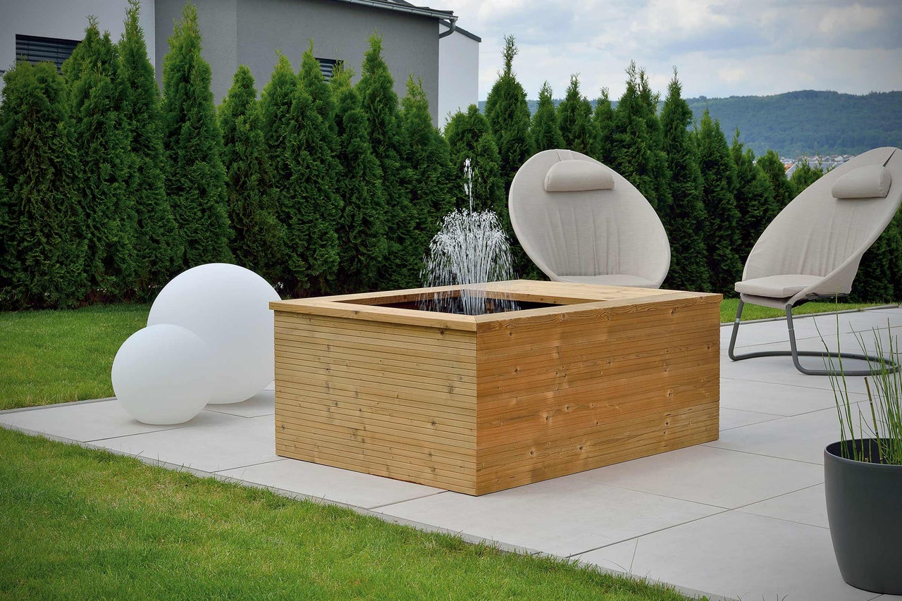 Scène de jardin avec fontaine en bois, luminaires de jardin et chaises de jardin