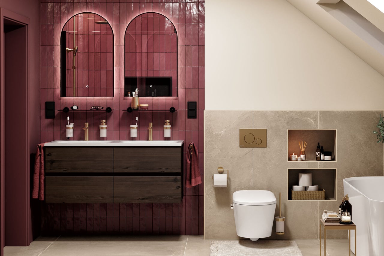 Salle de bain moderne avec double vasque sombre, deux miroirs cintrés, carrelage mural rouge, WC suspendu et carrelage en pierre beige.