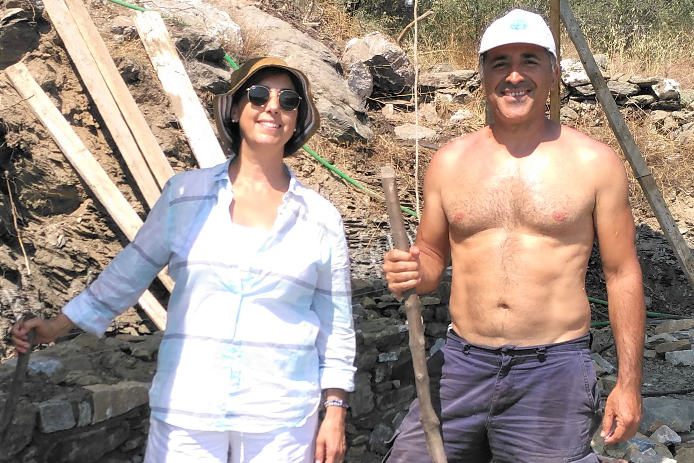 Frau und Mann bauen eine Trockenmauer mit Steinen und Holz