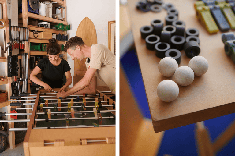 Deux personnes réparent un baby-foot dans un atelier; des pièces de rechange sont à disposition.