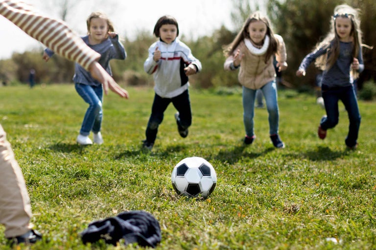 Des enfants jouent au football sur une pelouse.