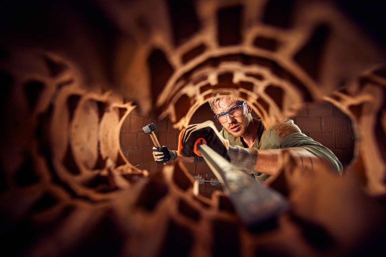 Homme avec lunettes de protection, marteau et burin lors de travaux de construction avec des briques