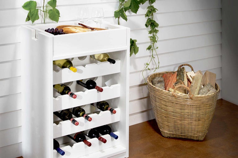 Casier à vin en bois avec bouteilles de vin remplies, pain, raisins et panier à bois