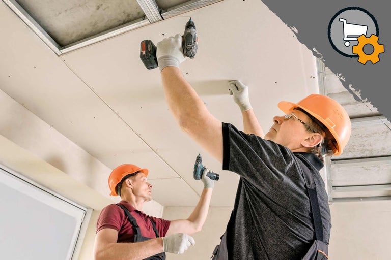 Deux ouvriers montent un plafond en plaques de plâtre avec une visseuse sans fil.
