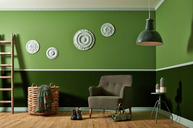 Pièce lumineuse avec murs verts, fauteuil, lampe et éléments décoratifs.