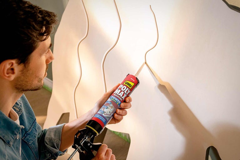 Un homme utilise de la colle de montage UHU Poly Max sur un habillage mural.