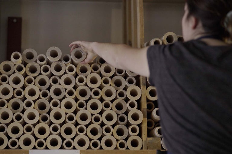 Aufnahme von runden Abstandshaltern aus Holz, die in einem Regal gestapelt sind, wobei eine Person einen Abstandshalter herausnimmt.