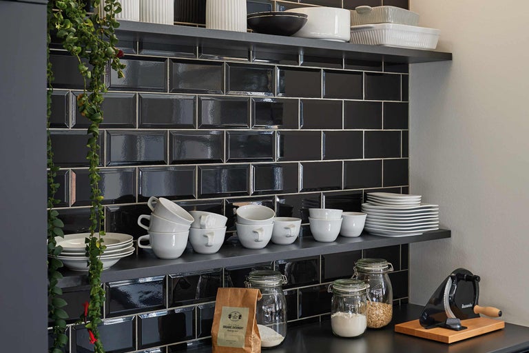 Étagères avec vaisselle et carreaux noirs dans la cuisine