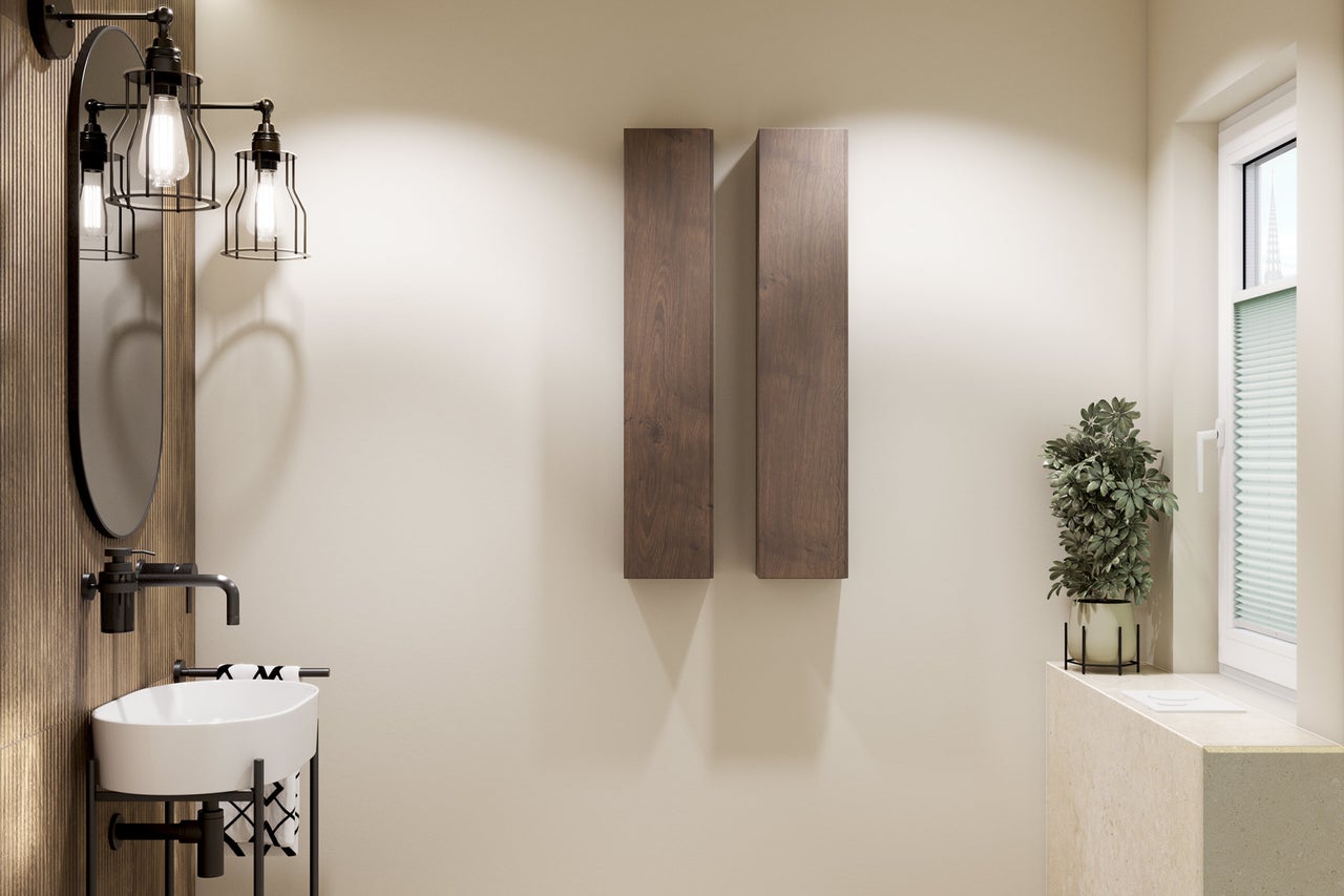 Salle de bains moderne avec lavabo blanc, robinetterie noire, miroir ovale et deux meubles hauts verticaux en aspect bois.