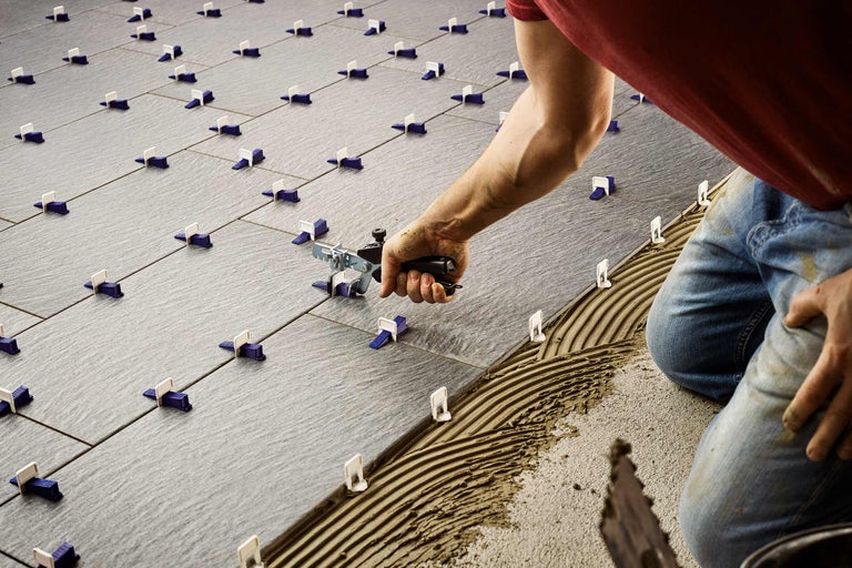 Pose de carreaux de sol avec système de nivellement de carreaux et outils