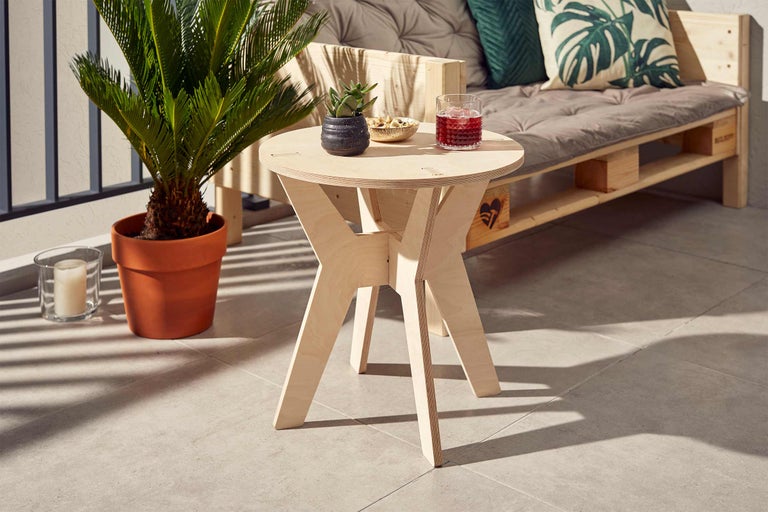 Table d'appoint ronde en bois clair sur un balcon avec boisson et décoration