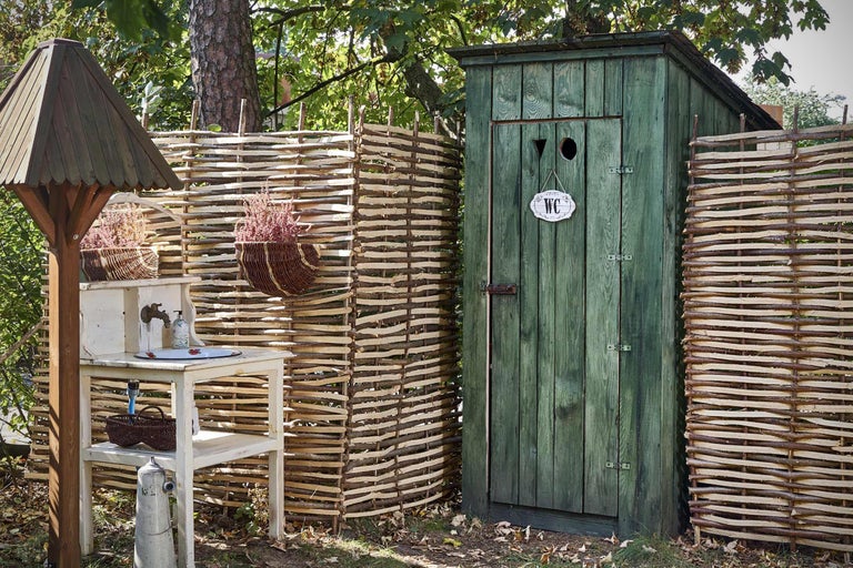Scène de jardin avec toilettes, lavabo et clôture en bois