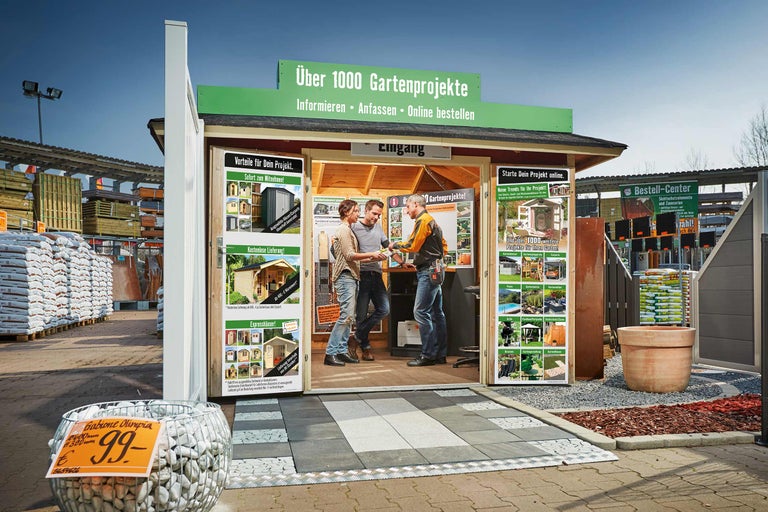 Vue extérieure d'un stand d'information pour projets de jardin avec deux clients et un vendeur