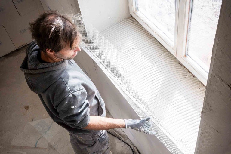 Artisan fixant un tissu d'armature sur une fenêtre