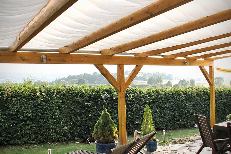 Terrasse couverte en bois avec voile d'ombrage et vue sur le jardin