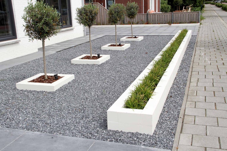 Jardin avec des arbres dans des jardinières carrées, une jardinière oblongue et du gravier
