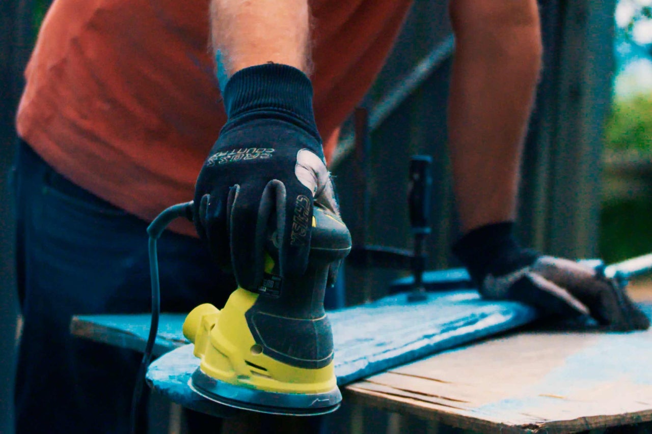 Une personne ponce du bois avec une ponceuse excentrique.