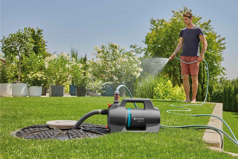Scène de jardin avec un homme arrosant des plantes avec une pompe de jardin Gardena