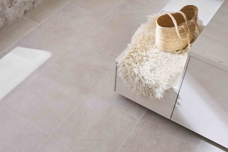 Carreaux de sol beiges dans une pièce avec banc, peau de mouton et panier