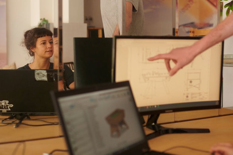 Des personnes travaillent sur des ordinateurs avec un dessin technique à l'écran