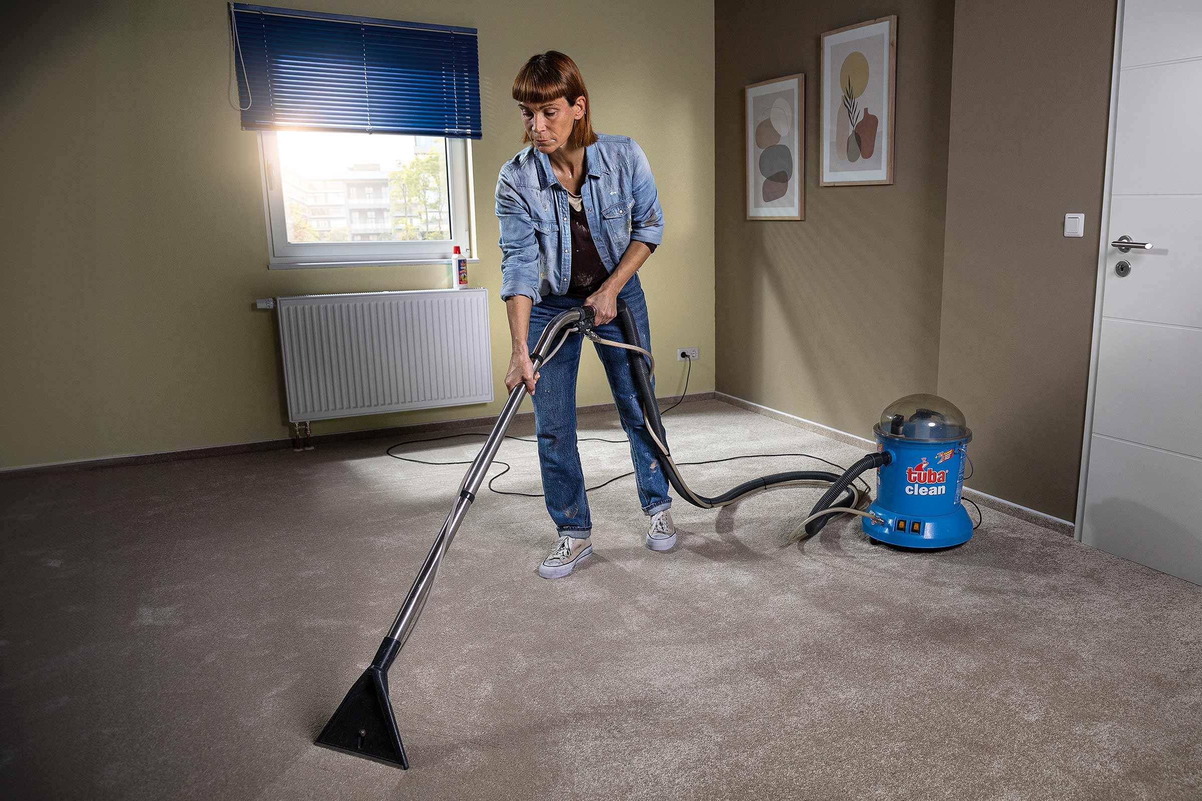 Une femme nettoie un tapis avec un appareil de nettoyage de tapis dans une pièce.