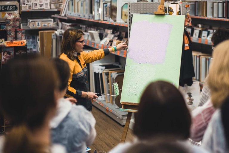 Une personne montre comment appliquer de la peinture sur une toile avec un rouleau à peinture dans un magasin Hornbach.