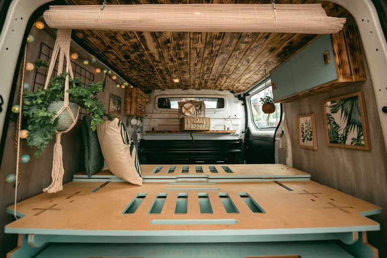 Innenraum eines umgebauten Vans mit Holzbett, Holzdecke und Dekorationen