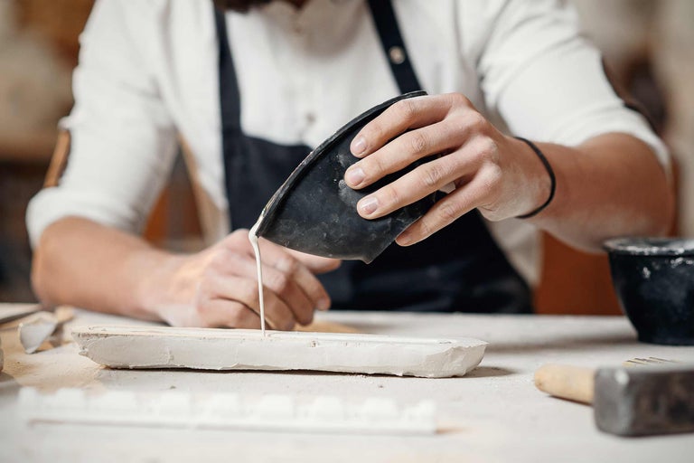 Handwerker giesst Gips in eine Gipsform.
