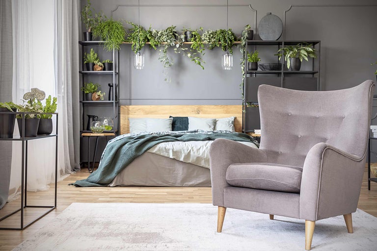 Chambre à coucher avec lit, fauteuil, étagères et plantes d'intérieur