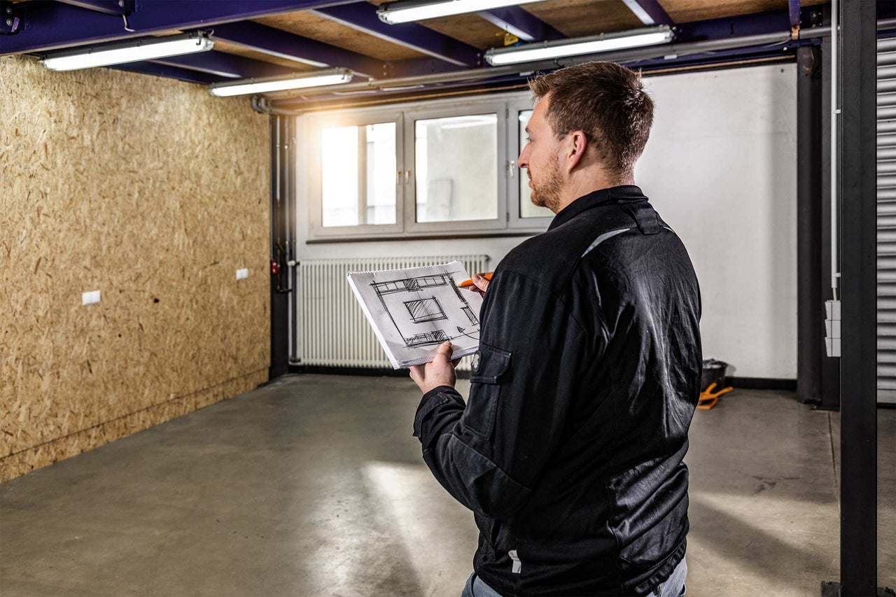 Homme avec plan dans un entrepôt avec éclairage