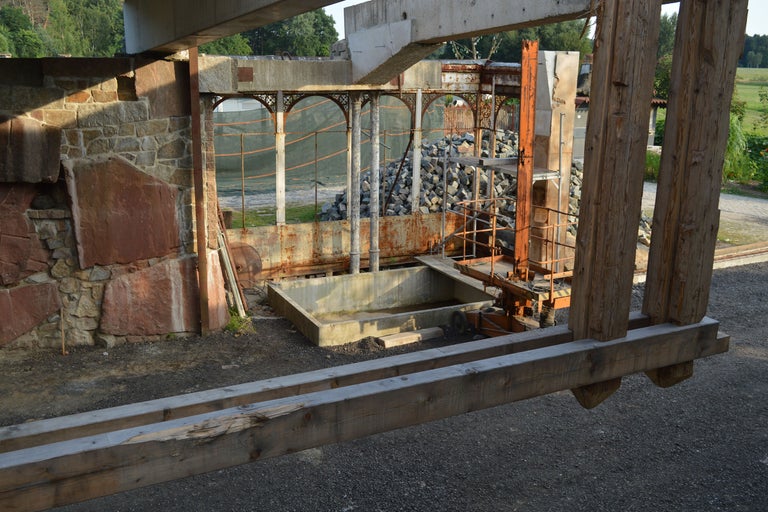 Ansicht einer Baustelle mit Steinmauer, Betonkonstruktionen und Holzbalken.